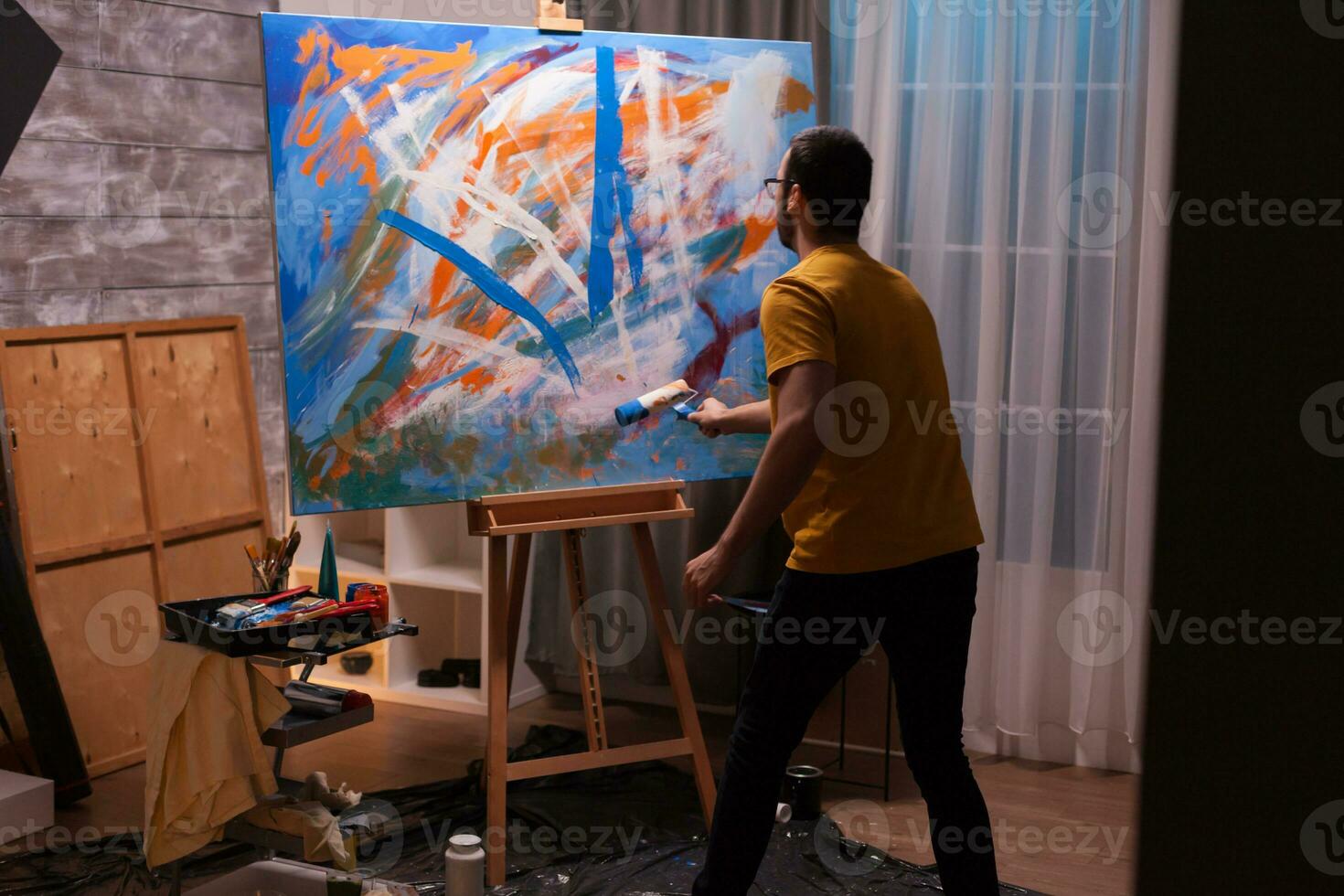 homme paiting avec rouleau sur Toile dans art studio. moderne ouvrages d'art peindre sur toile, créatif, contemporain et réussi bien art artiste dessin chef-d'oeuvre photo