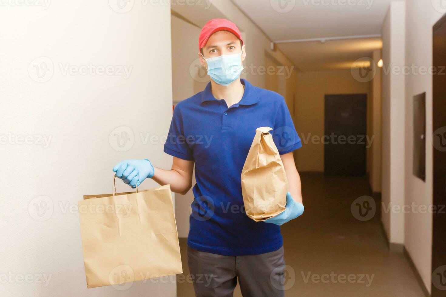 livraison homme en portant papier carton des boites dans caoutchouc gants et masque. en ligne achats et Express livraison photo