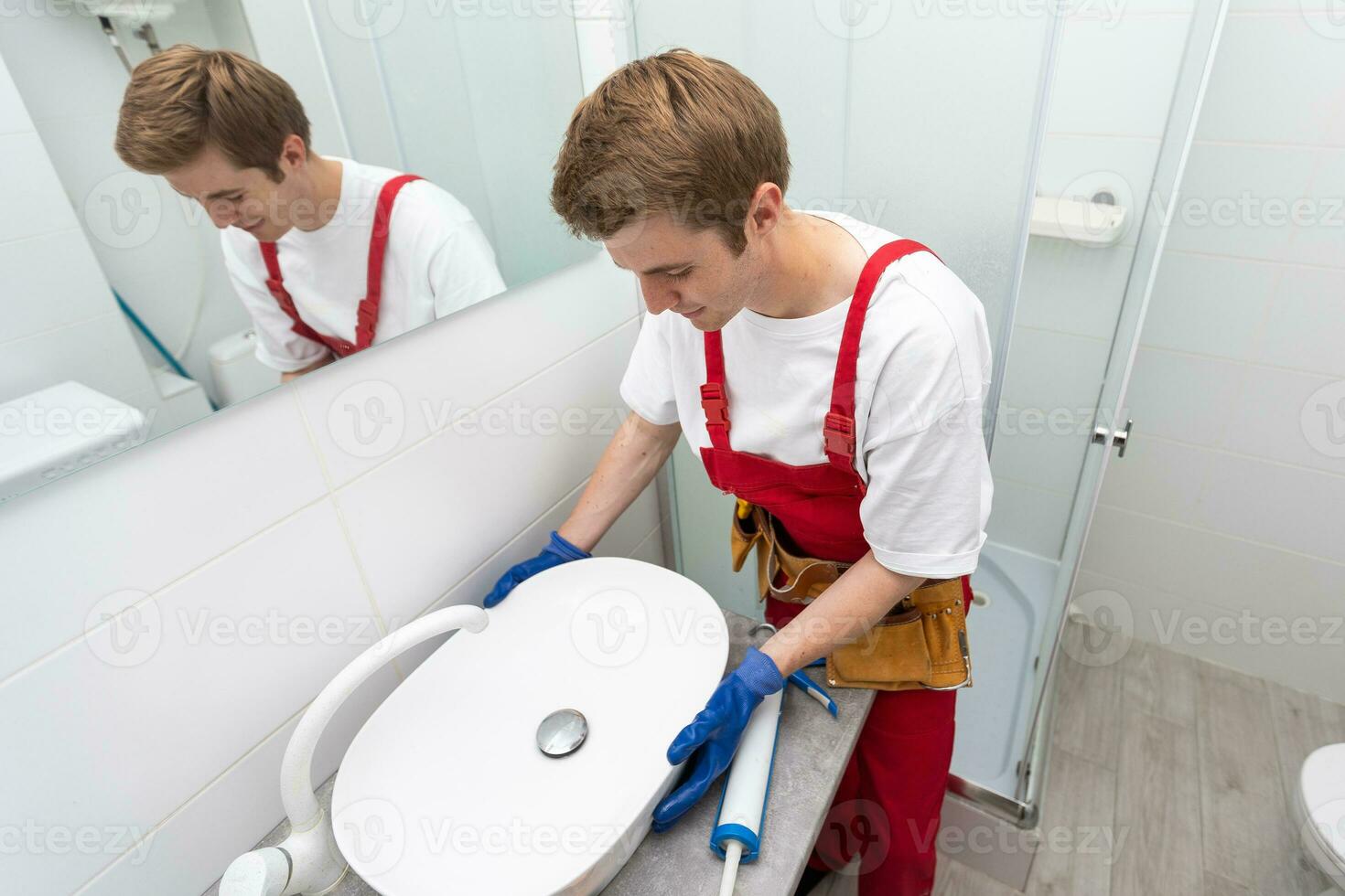 une ouvrier installe une laver bassin dans une salle de bains. photo