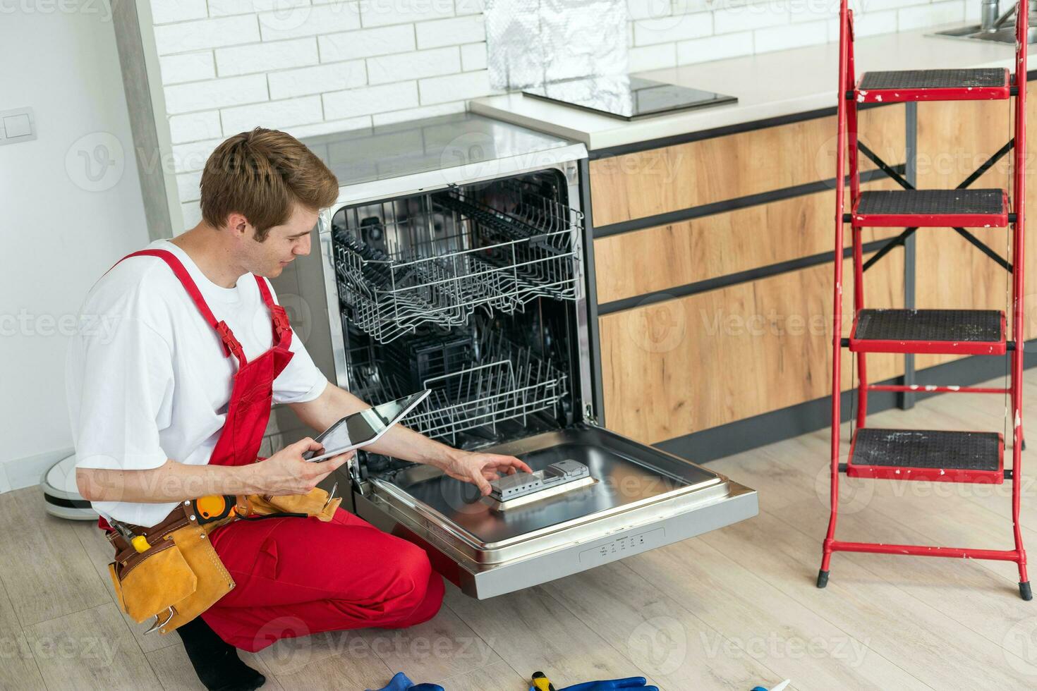 plein longueur de dépanneur réparer Lave-vaisselle avec Tournevis dans cuisine. photo