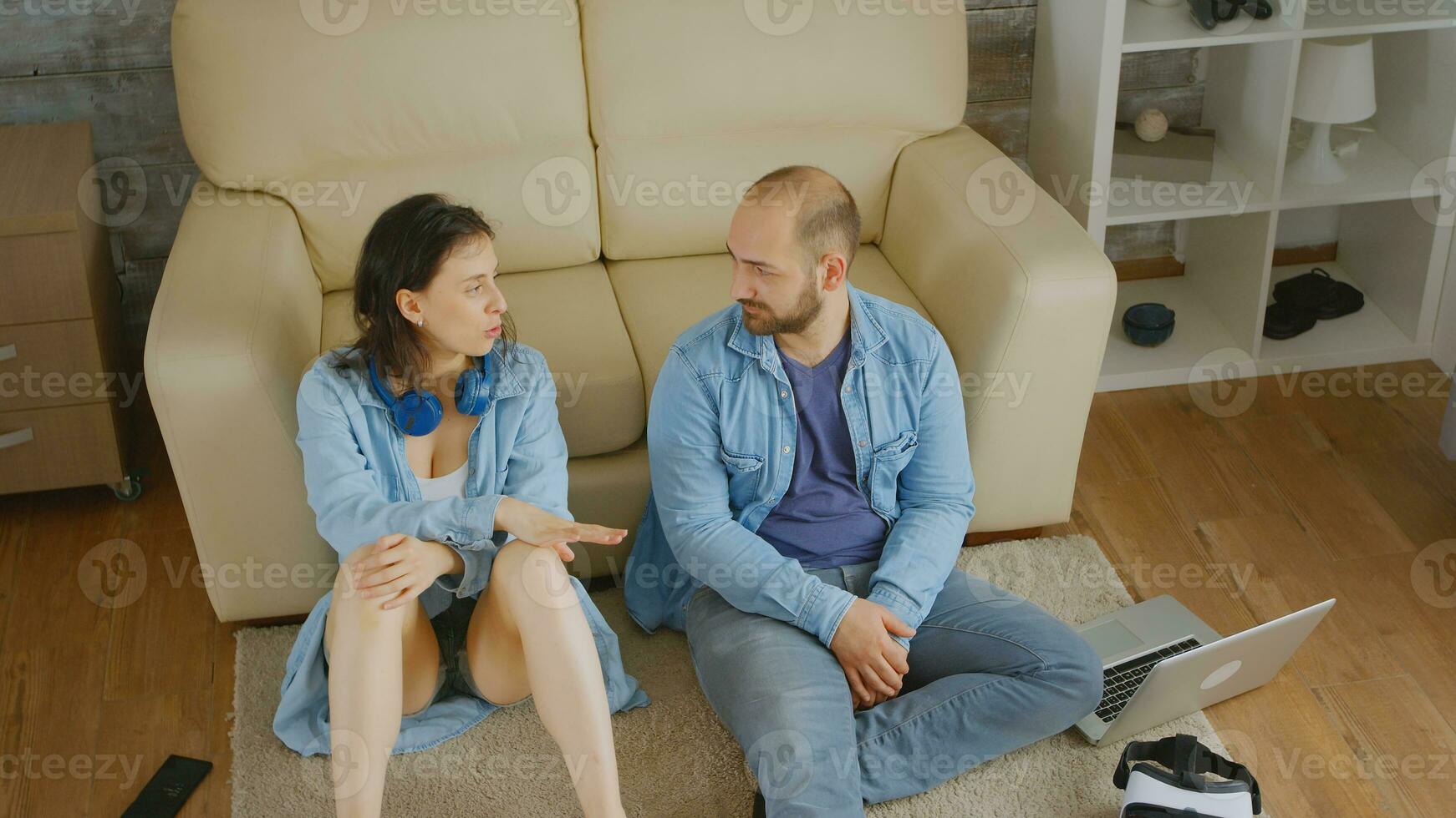 Haut vue de couple ayant une conversation séance près canapé sur tapis. photo