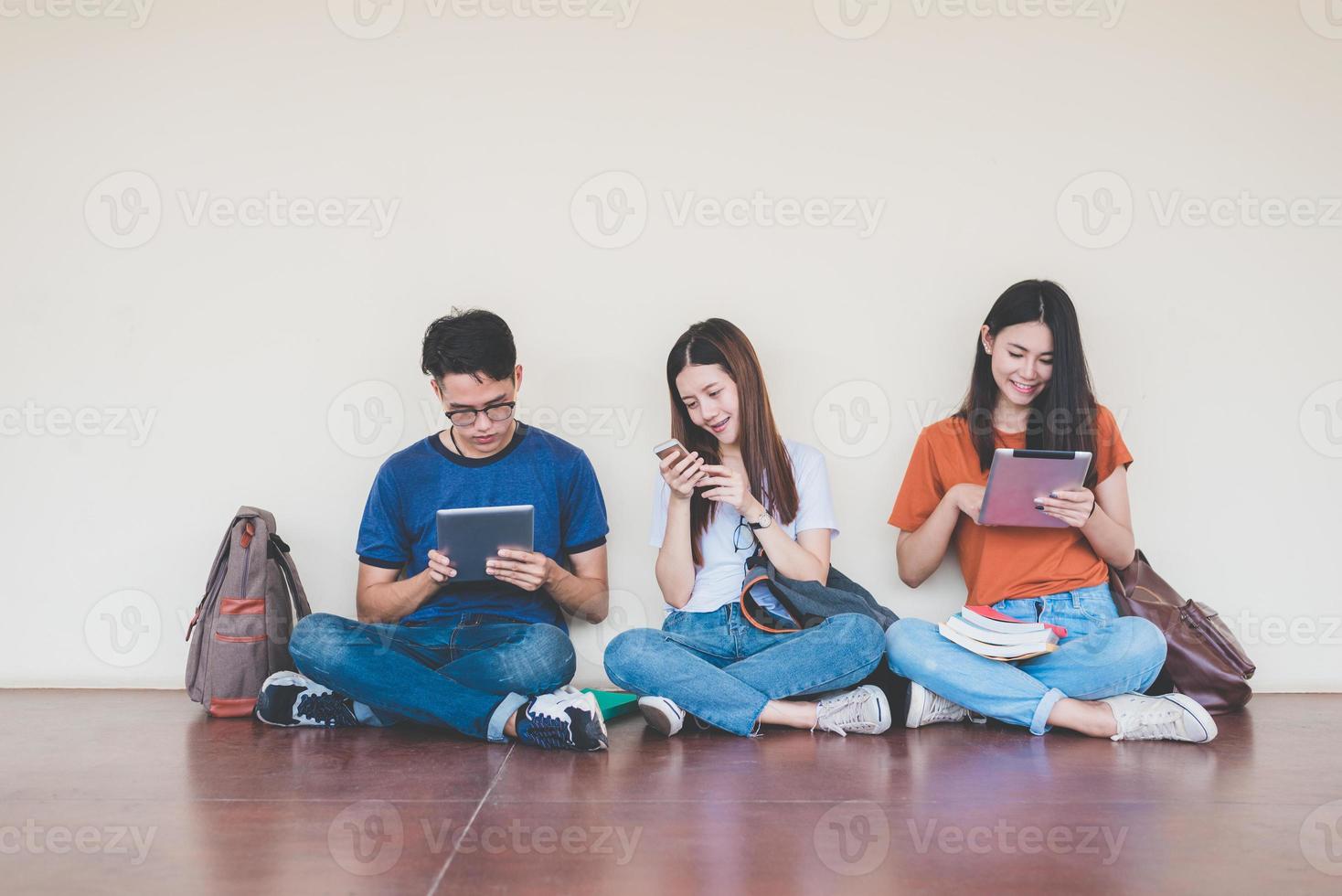 groupe d'étudiants asiatiques utilisant une tablette et un téléphone portable à l'extérieur de la salle de classe. concept d'apprentissage du bonheur et de l'éducation. retour au concept de l'école. thème des adolescents et des personnes. thème plein air et technologie photo