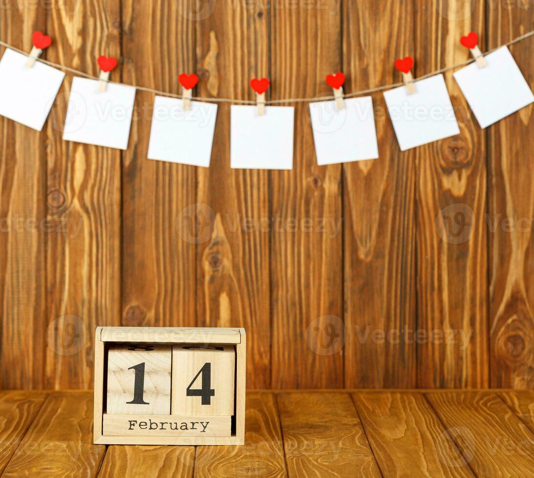 blanc pièces de papier sur pinces à linge avec une cœur sur une en bois arrière-plan, calendrier février 14 photo