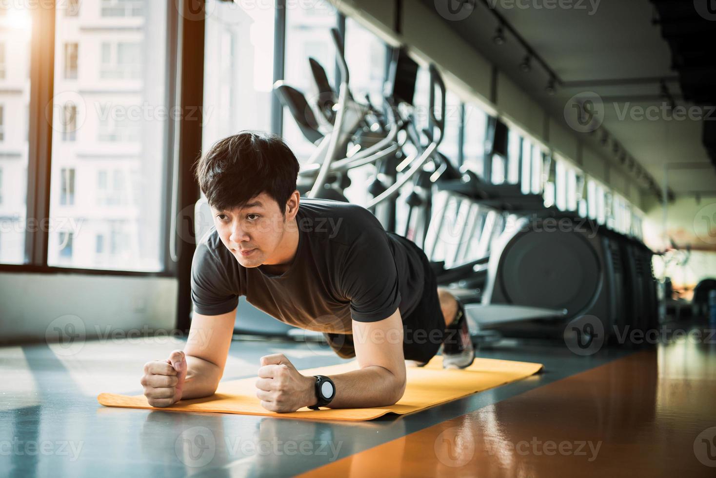 portrait d'un homme asiatique de remise en forme faisant des exercices de planche dans une salle de sport. concept de mode de vie et d'entraînement sportif des gens photo