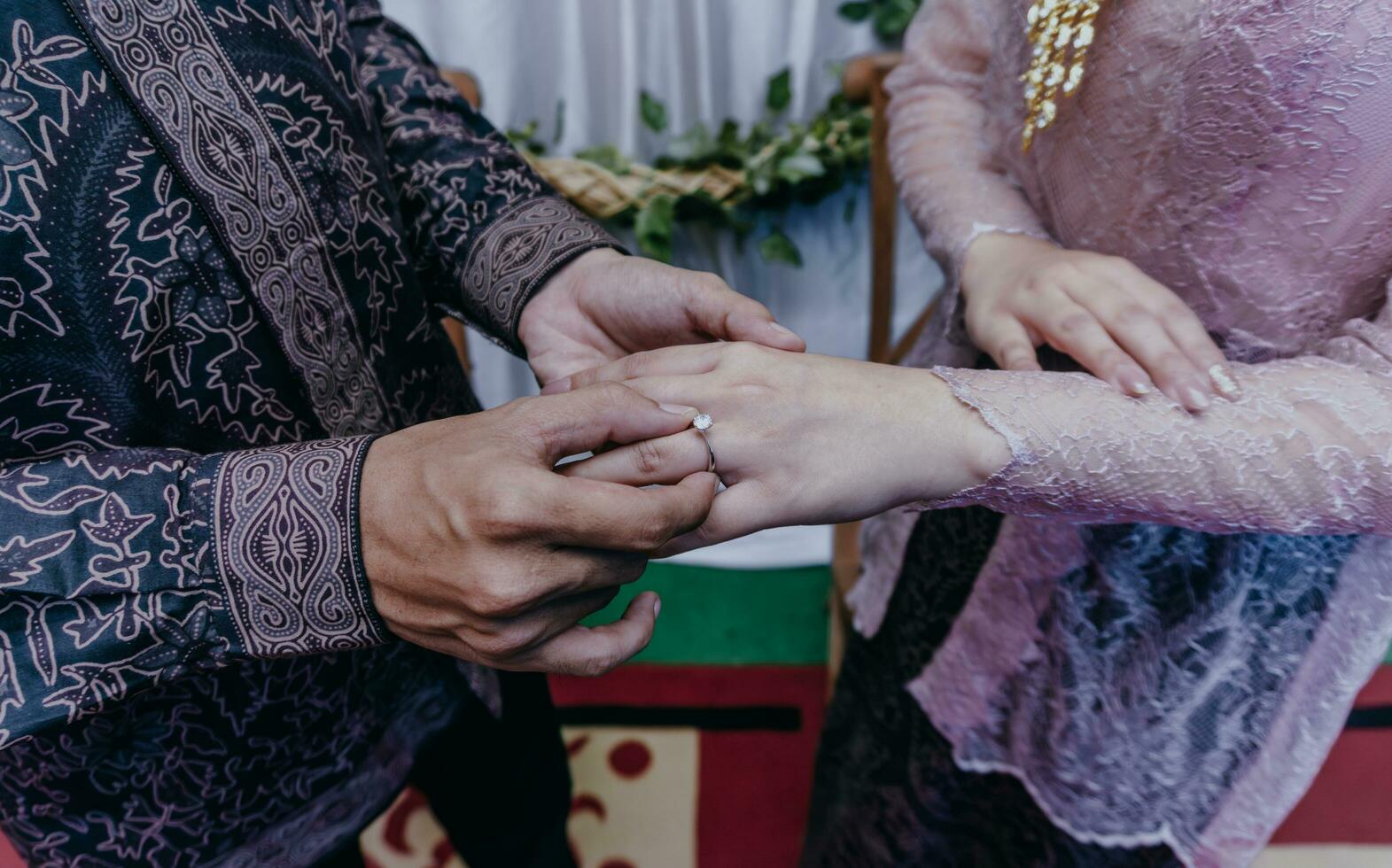 jeune marié met une bague sur le la mariée doigt. la cérémonie et mariage planification. or anneaux pour musulman les mariées dans Indonésie. photo