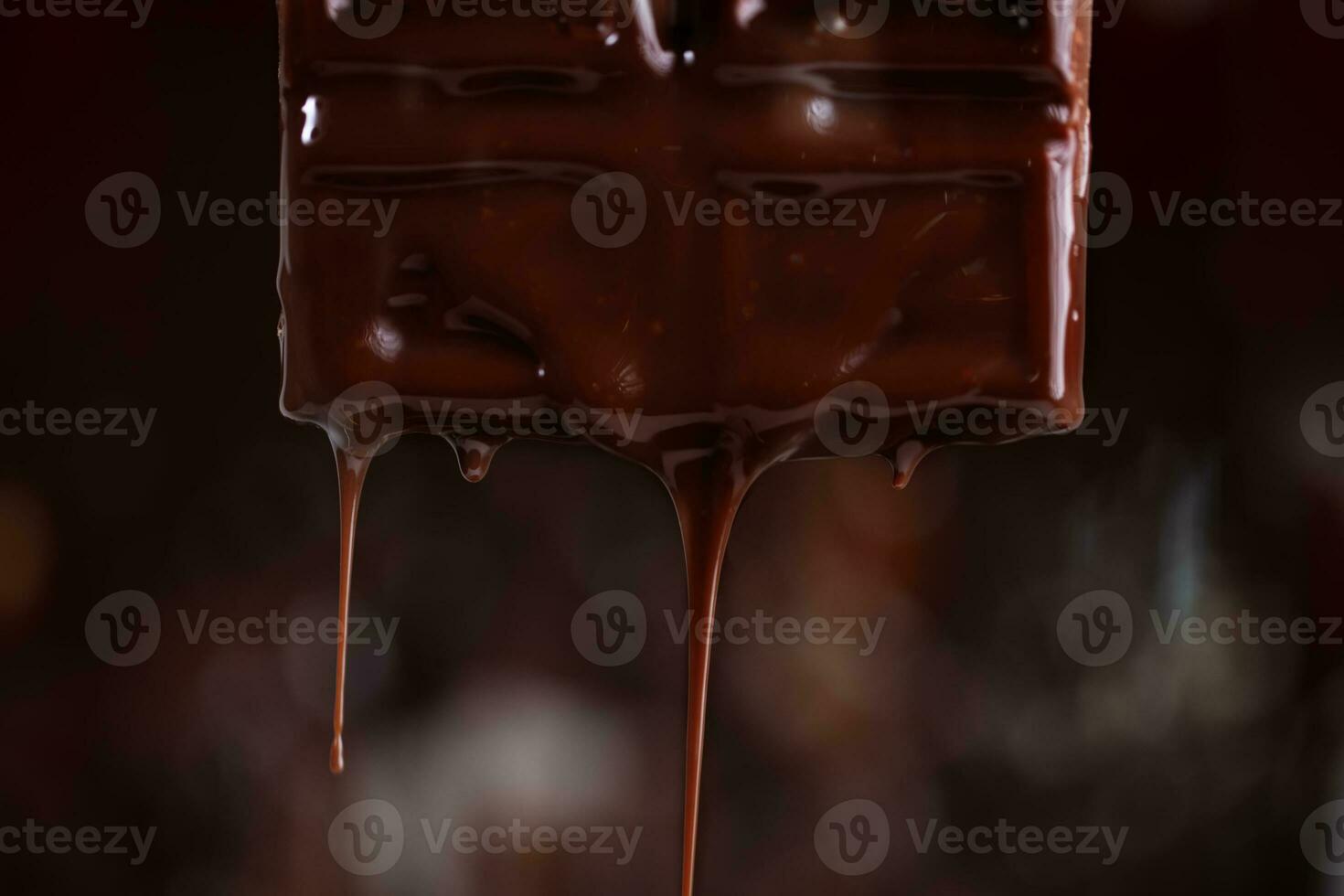 fondu Chocolat s'égoutte vers le bas sur une marron Contexte. photo