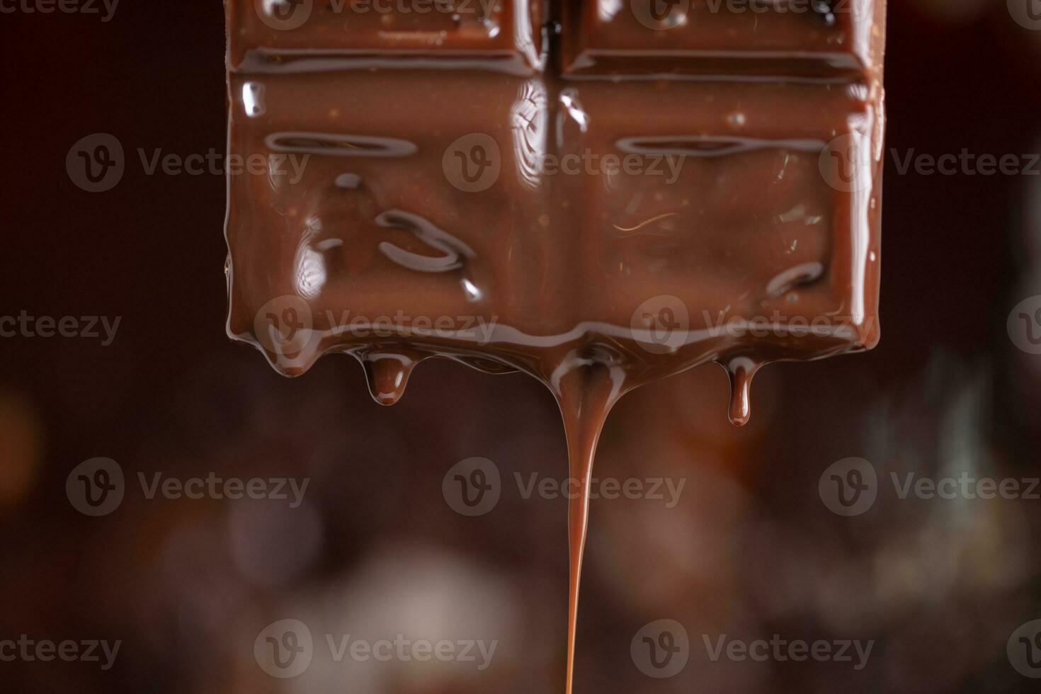 fondu Chocolat s'égoutte vers le bas sur une marron Contexte. photo