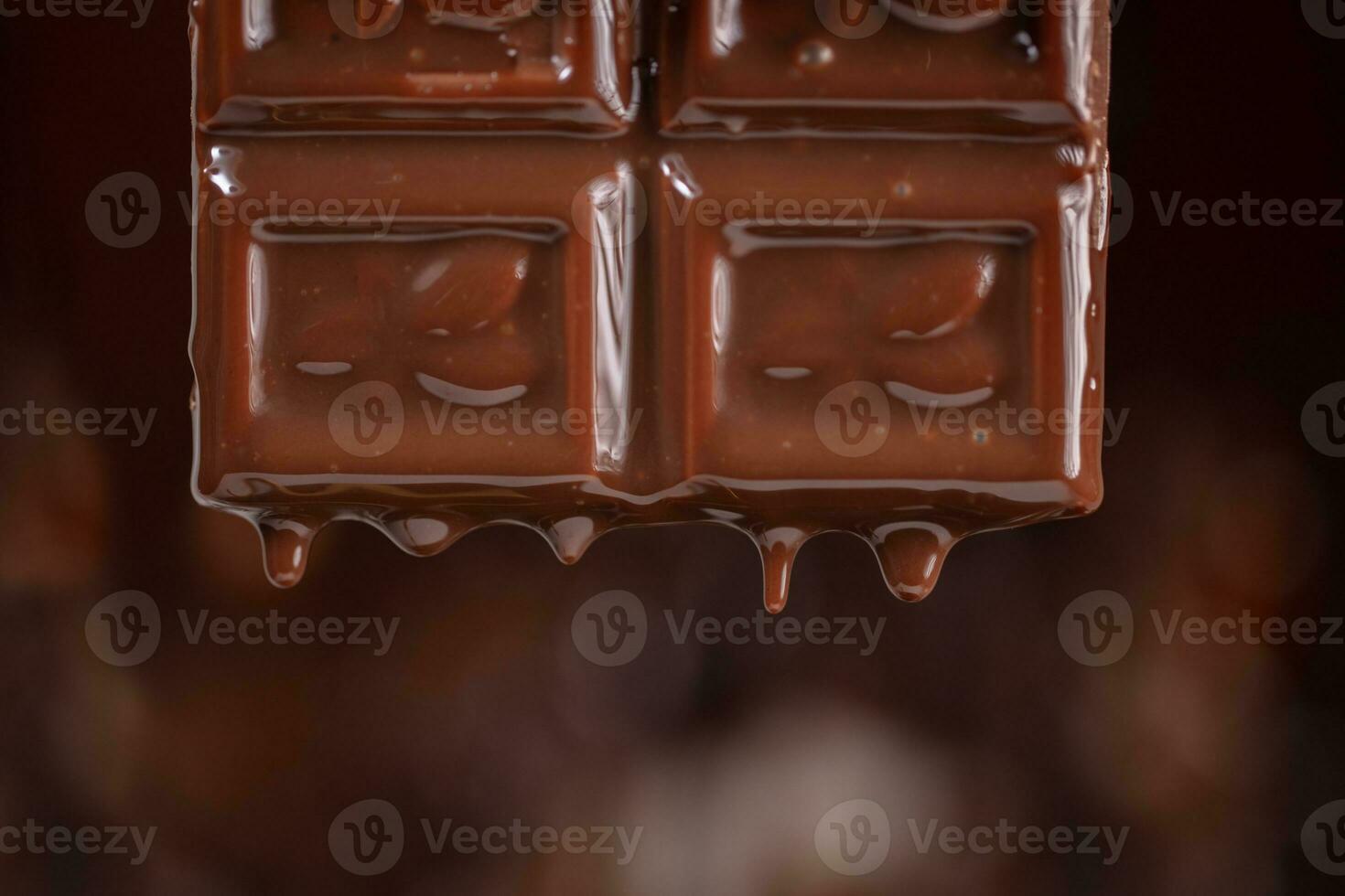 fondu Chocolat s'égoutte vers le bas sur une marron Contexte. photo