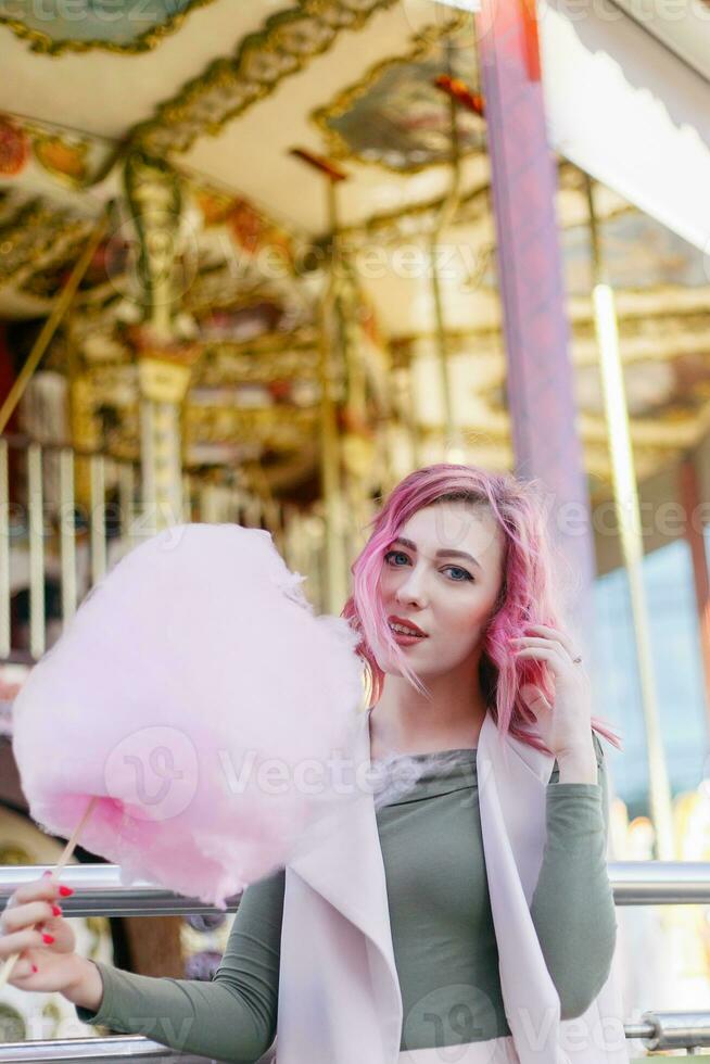 rose cheveux fille court la Coupe de cheveux posant dans amusement parc sur carrousel Contexte. photo