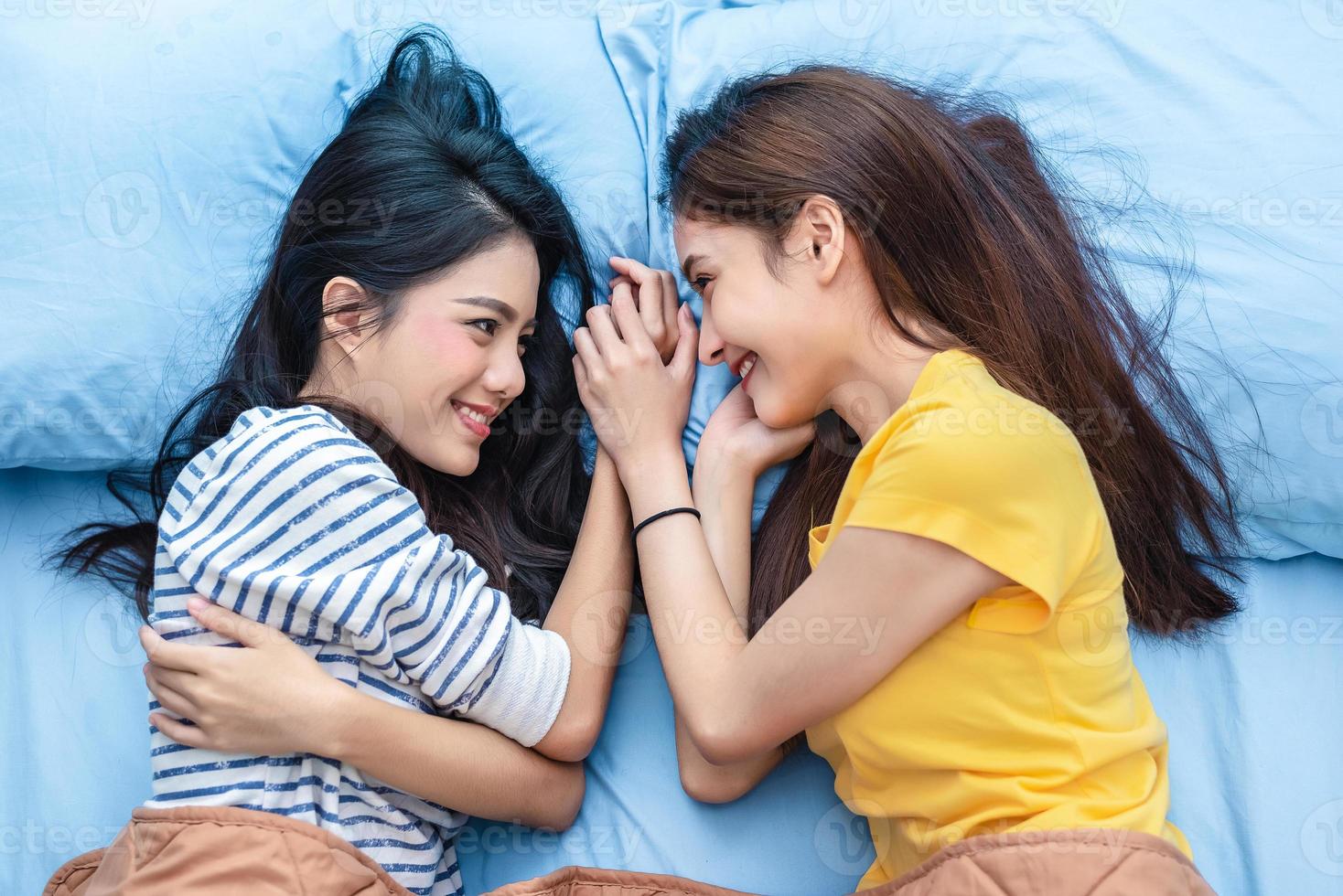 deux femmes asiatiques se regardant lorsqu'elles sont allongées sur le lit. concept de modes de vie et d'amoureux. vie de bonheur et concept de détente. thème de la vie homosexuelle. thème de la fierté lgbt et des couples de lesbiennes photo