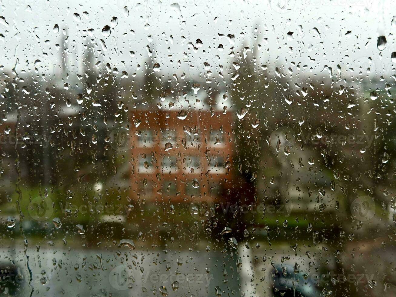 pluvieux journée dans le industriel ville. vue par humide fenêtre avec gouttes de pluie moment voyant industriel zone pendant pluie tempête. Contexte. photo