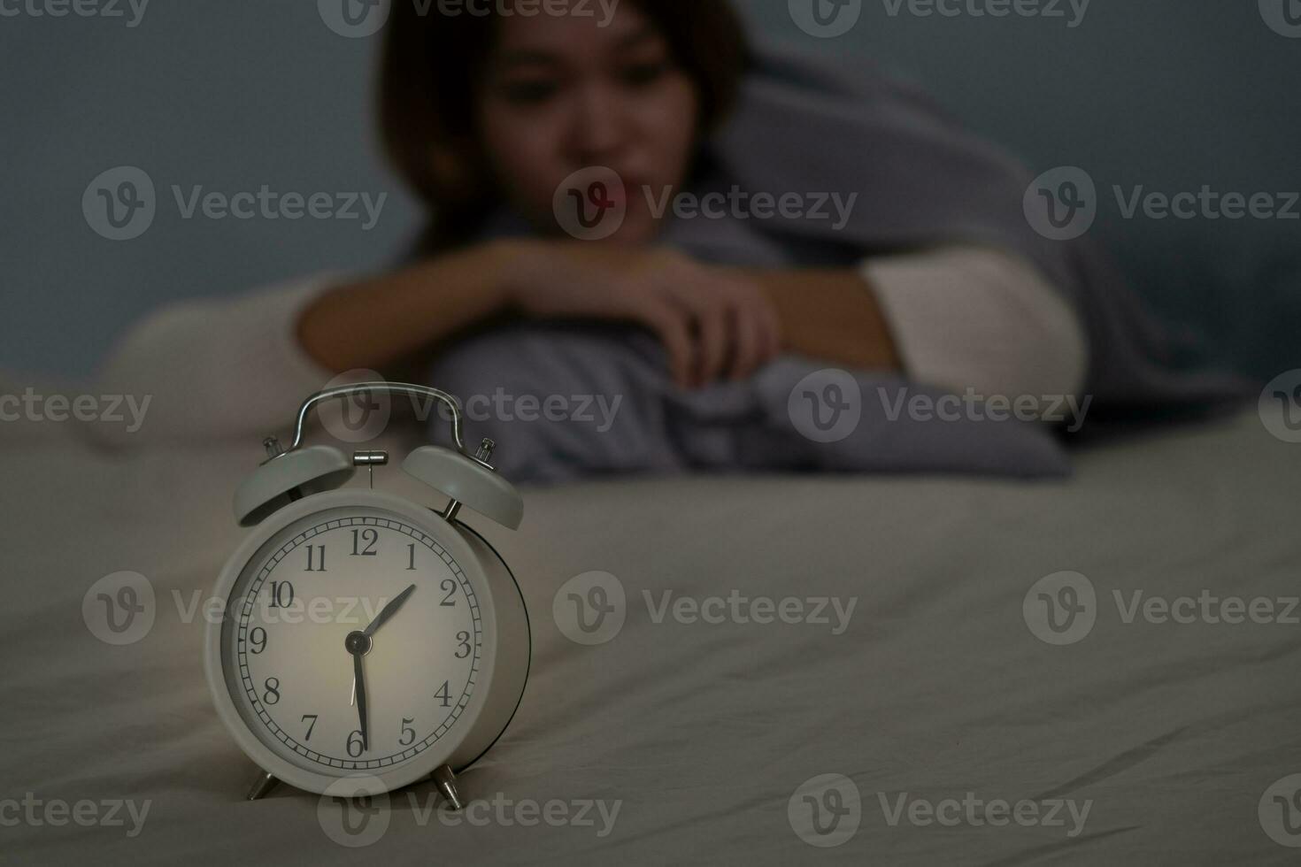 asiatique femme dans lit en retard en essayant à sommeil Souffrance insomnie, sans sommeil ou effrayé dans une cauchemar, à la recherche triste inquiet et stressé. fatigué et mal de crâne ou migraine veille en haut dans le milieu de le nuit. photo