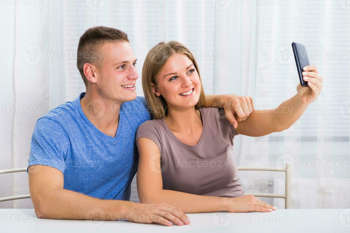 Jeune content couple séance à le table et prise selfie photo