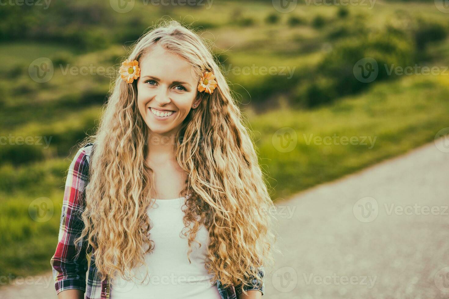 portrait de magnifique blond femme avec fleurs dans sa cheveux à le pays route.tonique image. photo