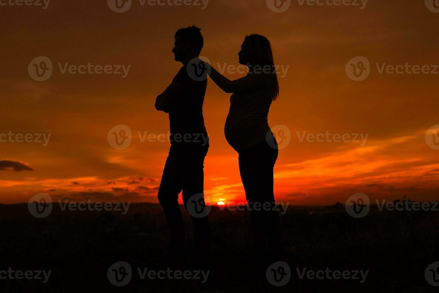 silhouettes de en colère mari et Enceinte épouse tandis que elles ou ils permanent extérieur.tonique image. photo