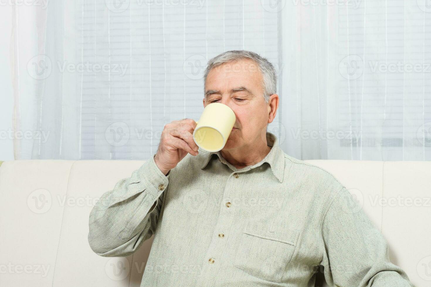 Sénior homme jouit en buvant café ou thé à maison. photo