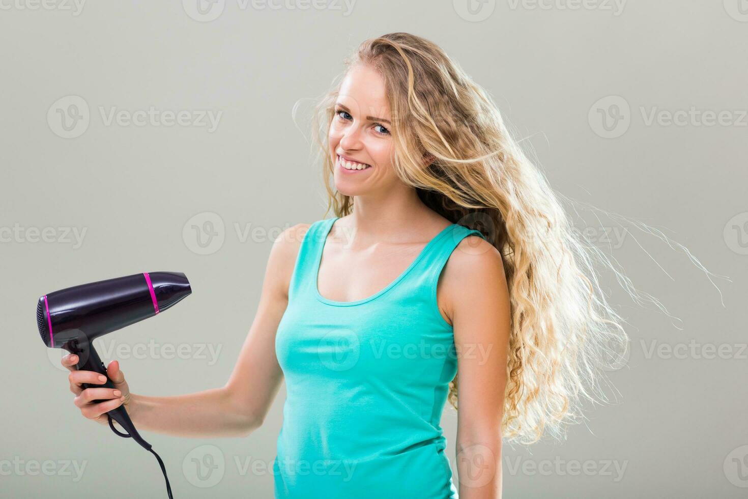 Jeune femme avec magnifique longue blond cheveux en utilisant Sèche-cheveux. photo