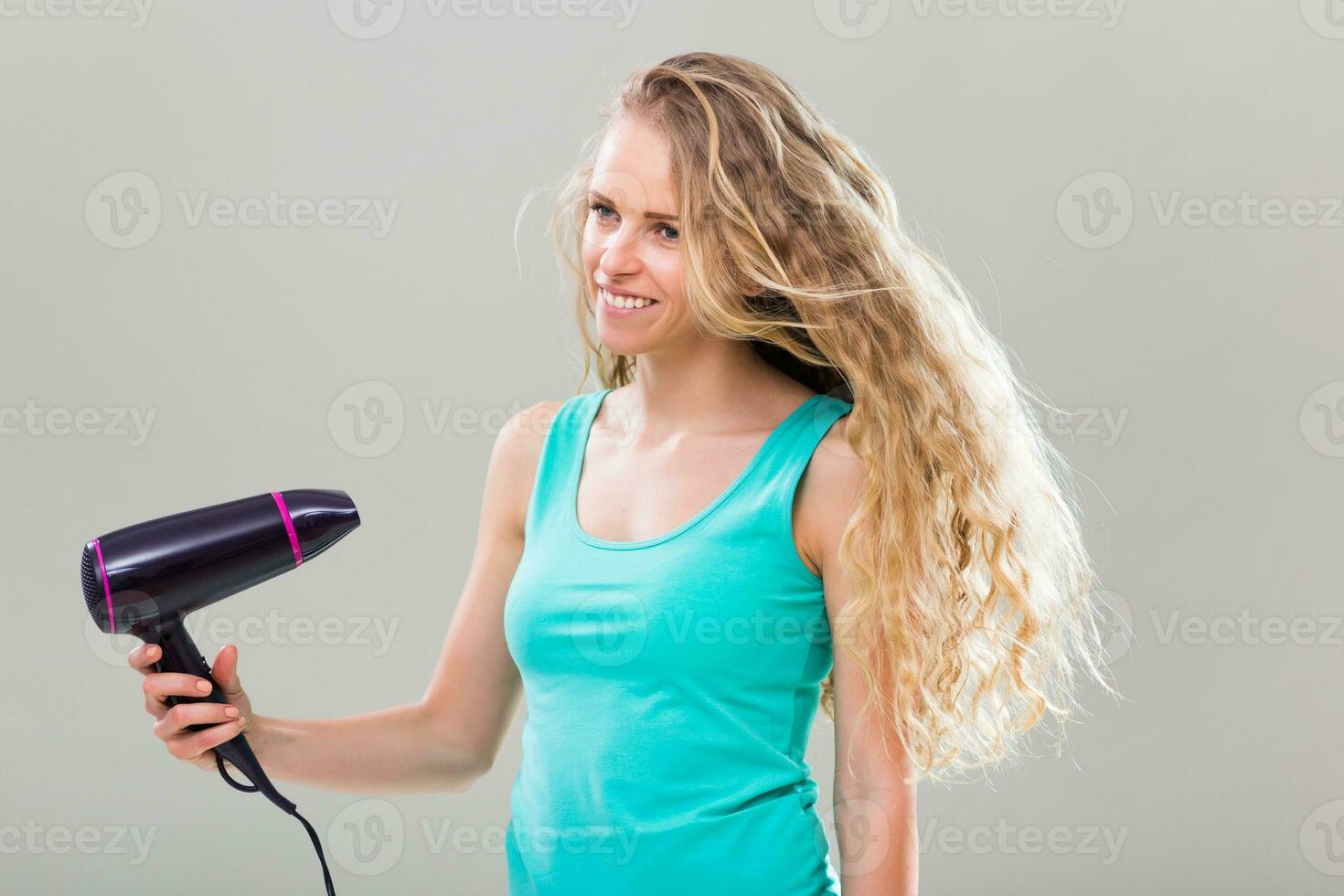 Jeune femme avec magnifique longue blond cheveux en utilisant Sèche-cheveux. photo