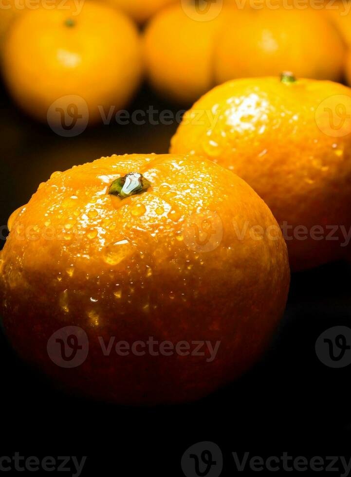 goutte d'eau sur une surface brillante de fraîcheur orange sur fond noir photo