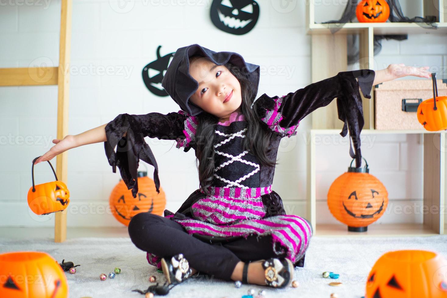 portrait de petite fille avec une robe de sorcière joue dans la chambre décorée au festival d'halloween photo