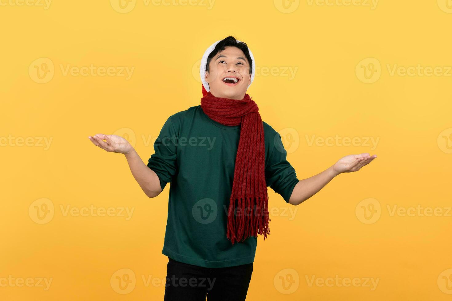attrayant Jeune asiatique homme portant sur le thème de Noël Vêtements et fabrication un ouvert paume geste Regardez pour séparé vide les espaces sur une Jaune Contexte. photo