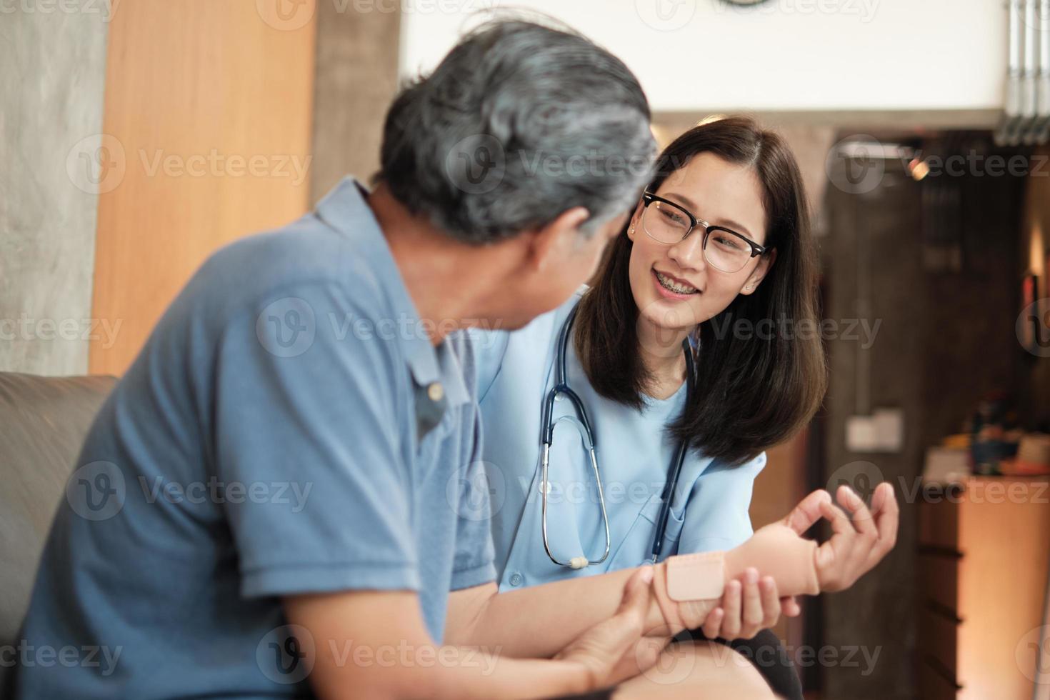 Un médecin thérapeute féminin examine un patient âgé à la maison. photo