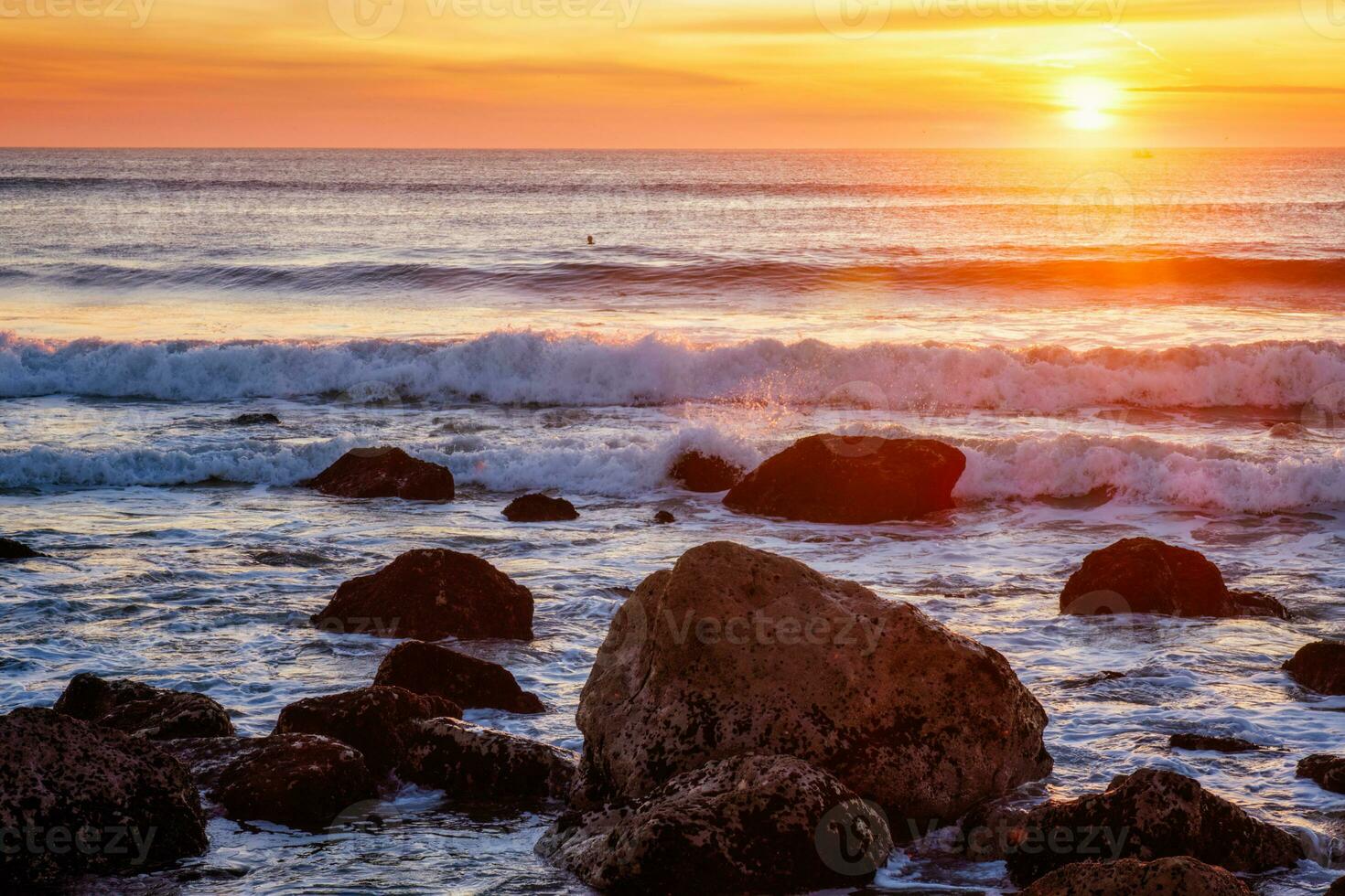 atlantique océan le coucher du soleil avec vagues et rochers à costa da caparica, le Portugal photo