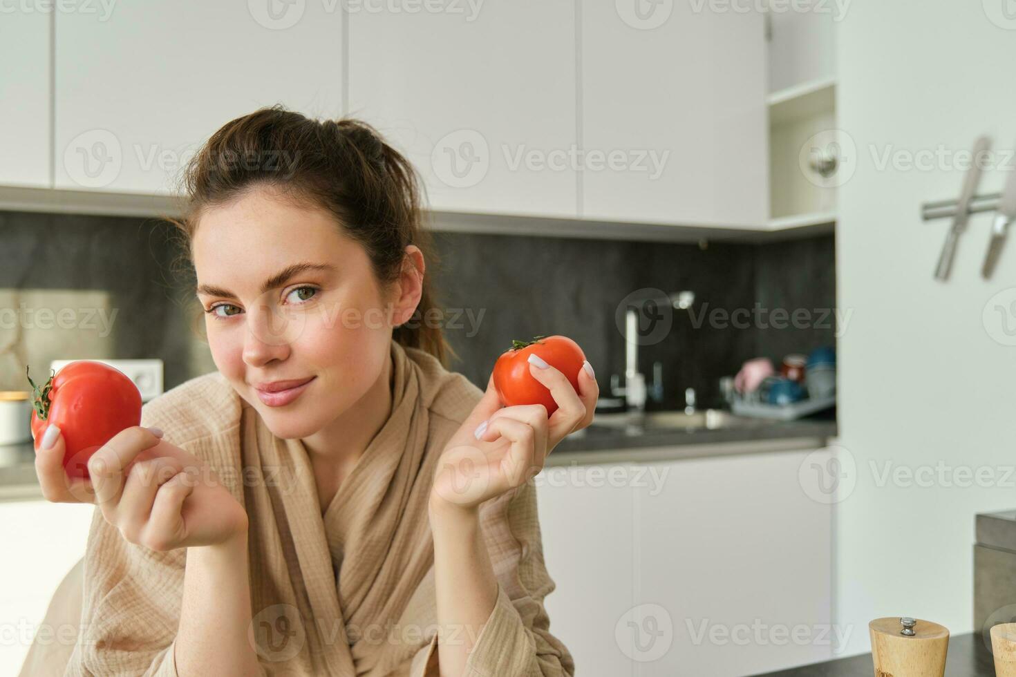 portrait de magnifique femme cuisine dans le cuisine, couper des légumes sur conseil, en portant tomates, conduire en bonne santé mode de vie avec en train de préparer Frais salades, végétalien repas photo
