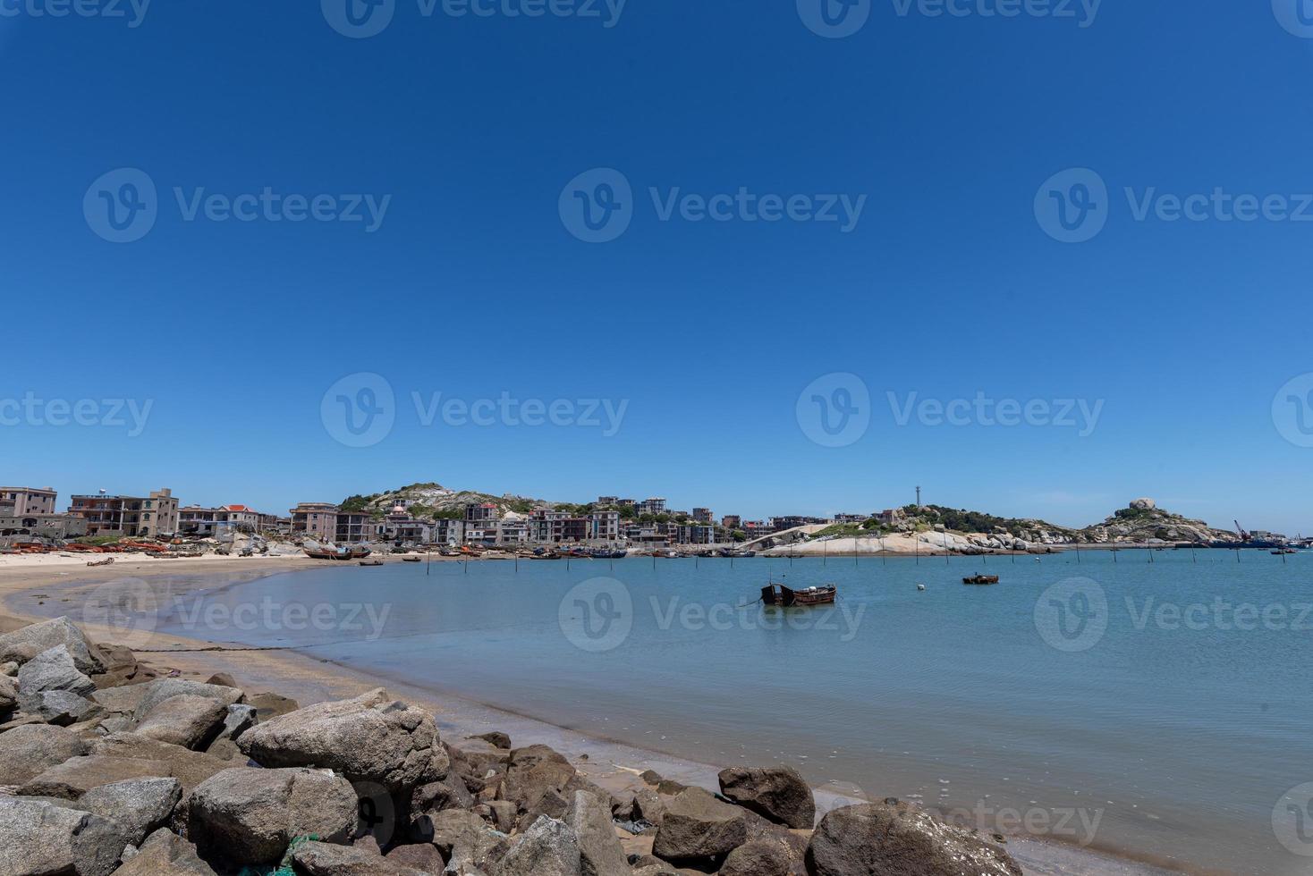 tenez-vous haut et regardez le paysage marin sous le ciel bleu, l'eau bleue, les vagues blanches et les rochers noirs photo