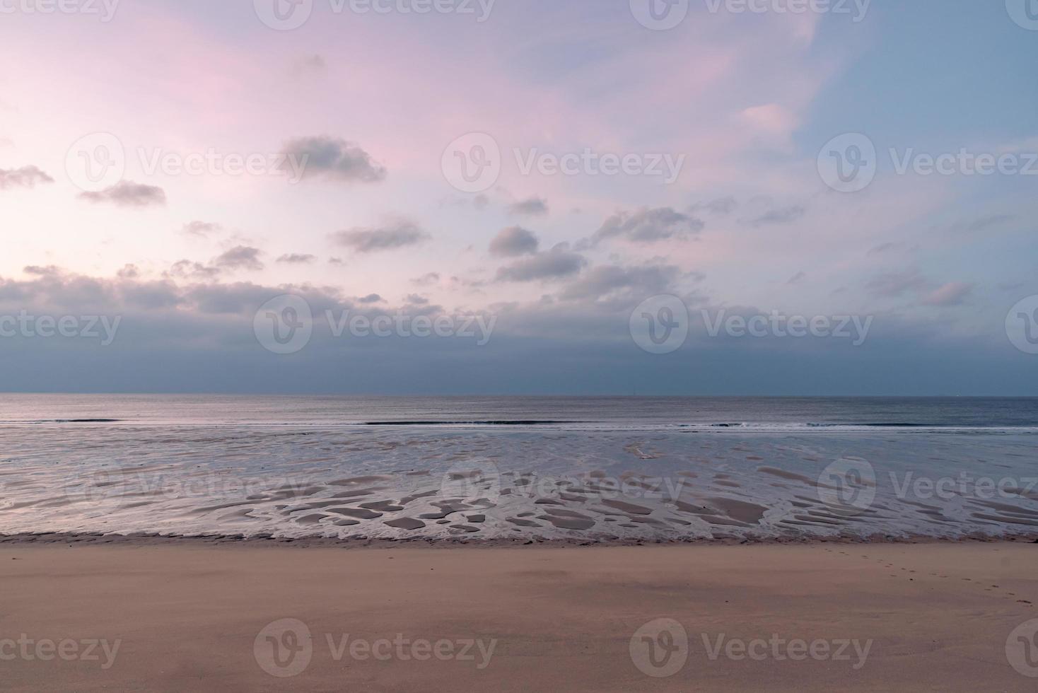 au petit matin au bord de la mer, le ciel et la plage sont légèrement rouges photo