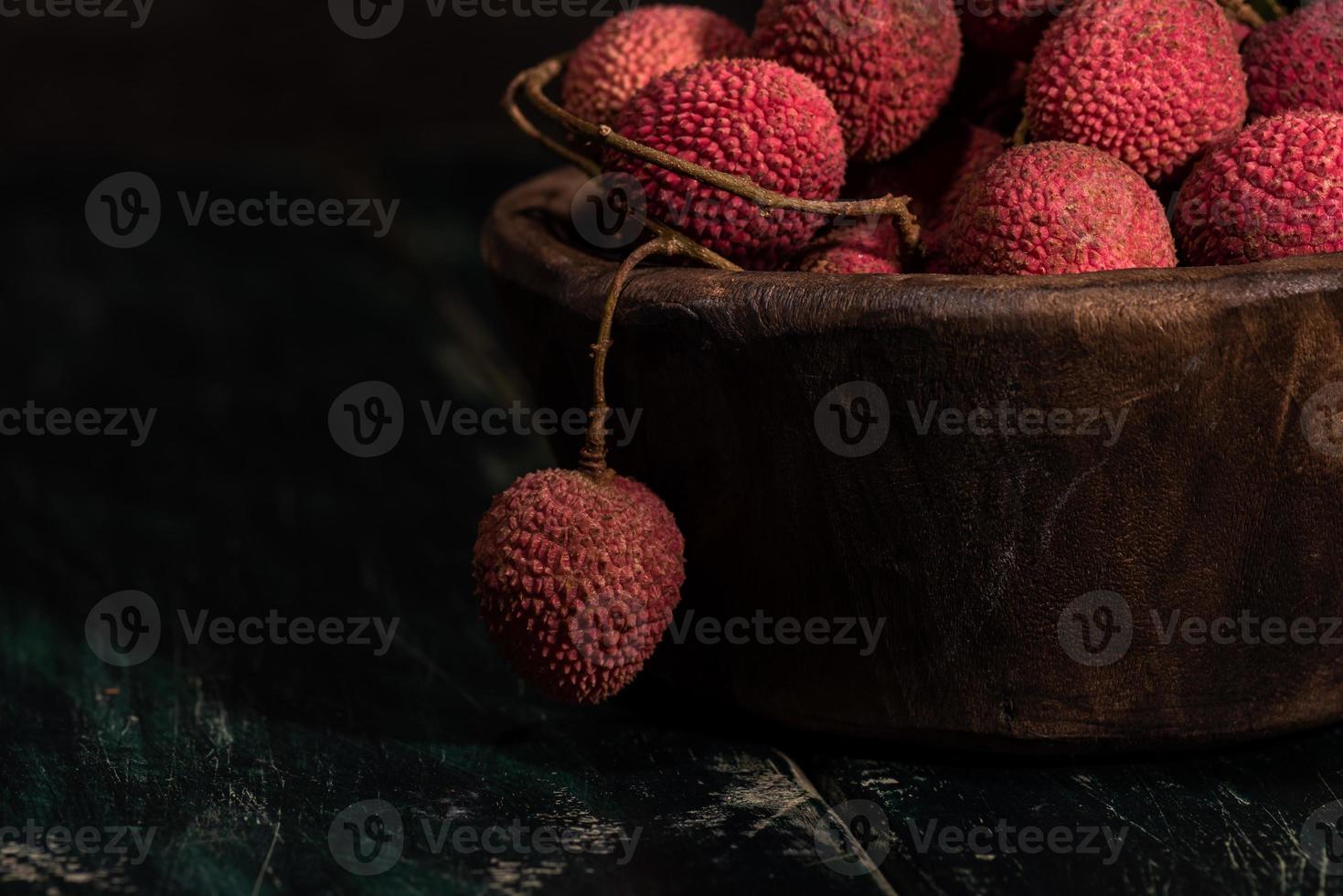 le litchi est placé dans une assiette en bois, pelée ou non ouverte, sur une table à grain de bois foncé photo