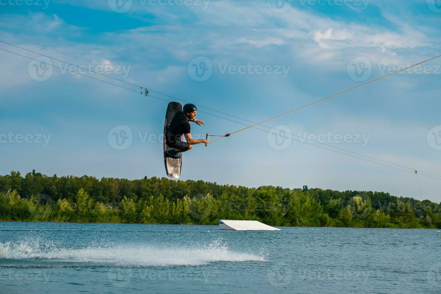 Masculin wakeboarder sauter plus de l'eau avec planche en portant corde photo