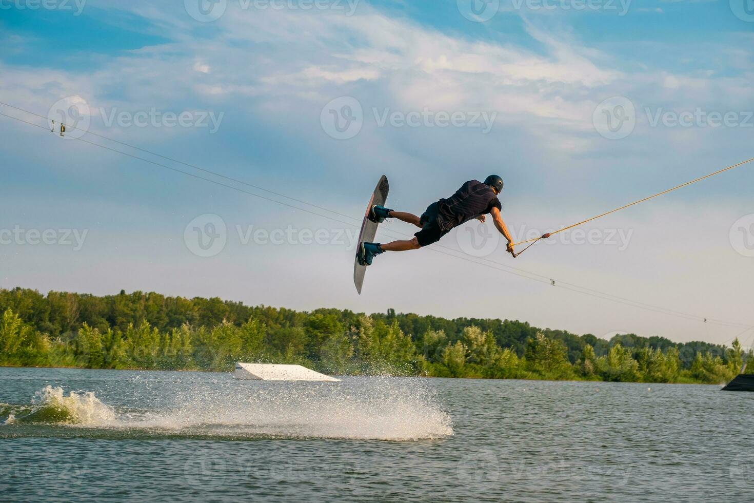 Masculin wakeboarder performant sauter plus de l'eau pendant été formation photo