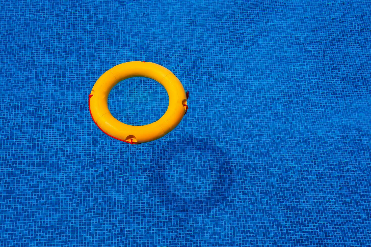 Haut vue de bouée de sauvetage flottant dans bleu nager piscine, doux se concentrer. photo