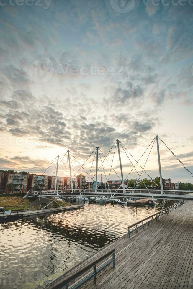 piéton et vélo pont plus de le port dans le centre de almère pendant le coucher du soleil. néerlandais moderne et utilitaire construction photo
