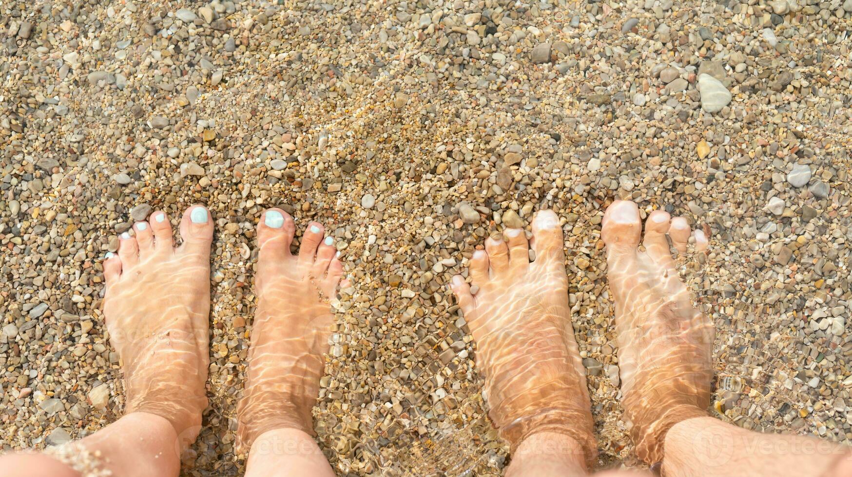 homme et femme pieds dans le l'eau dans le mer. vacances par le mer et relaxation sur le plage. fermer. photo