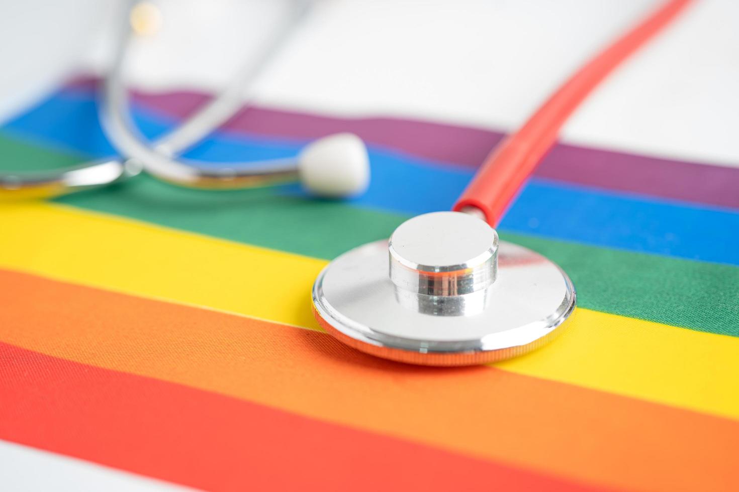 stéthoscope rouge sur fond de drapeau arc-en-ciel, symbole du mois de la fierté lgbt célèbre chaque année en juin social, symbole des gays, lesbiennes, bisexuels, transgenres, droits de l'homme et paix photo