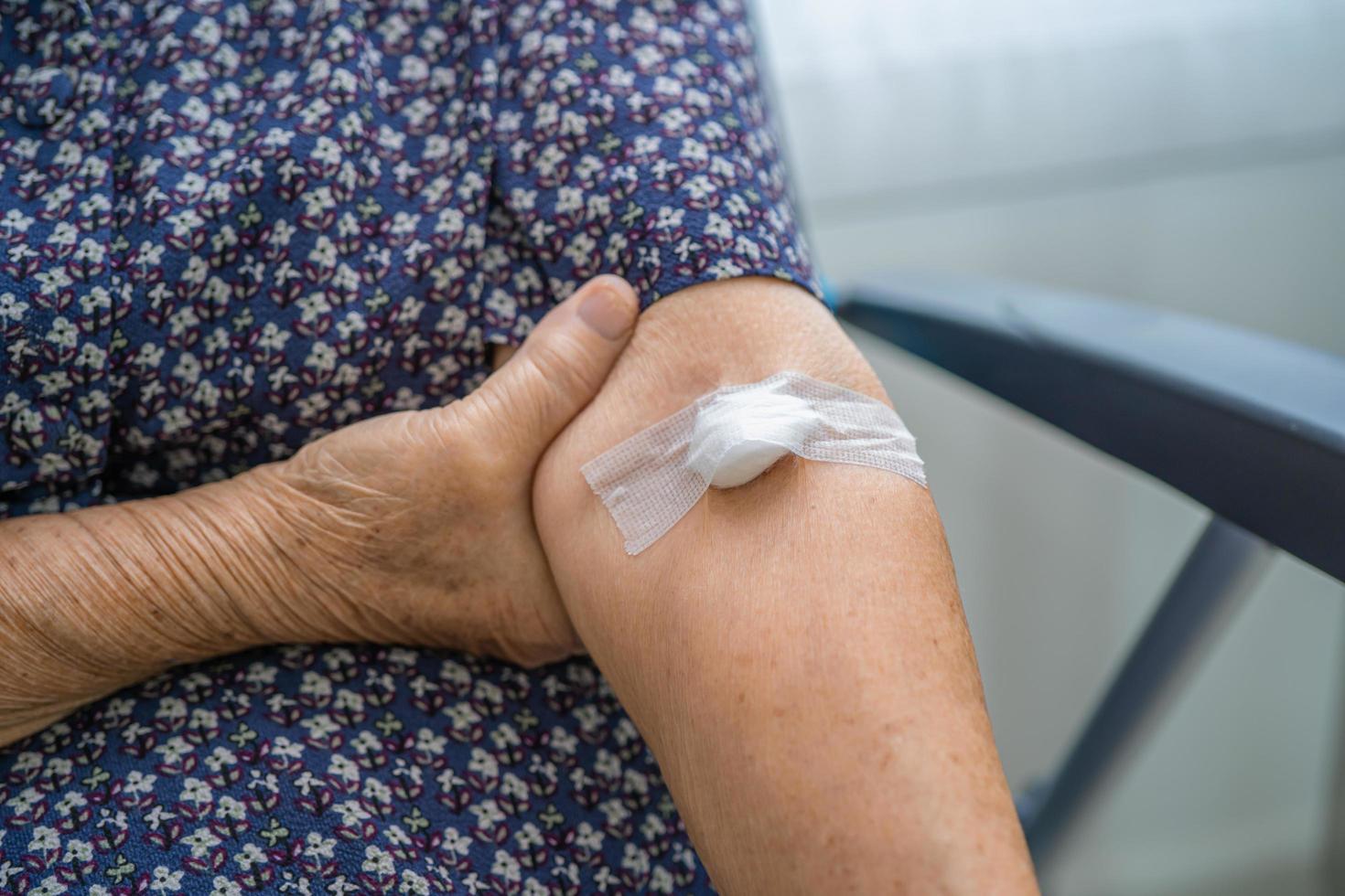 Une patiente asiatique âgée ou âgée montre un coton arrête de saigner, après des tests sanguins pour un bilan de santé physique annuel pour vérifier le cholestérol, la pression artérielle et le niveau de sucre photo