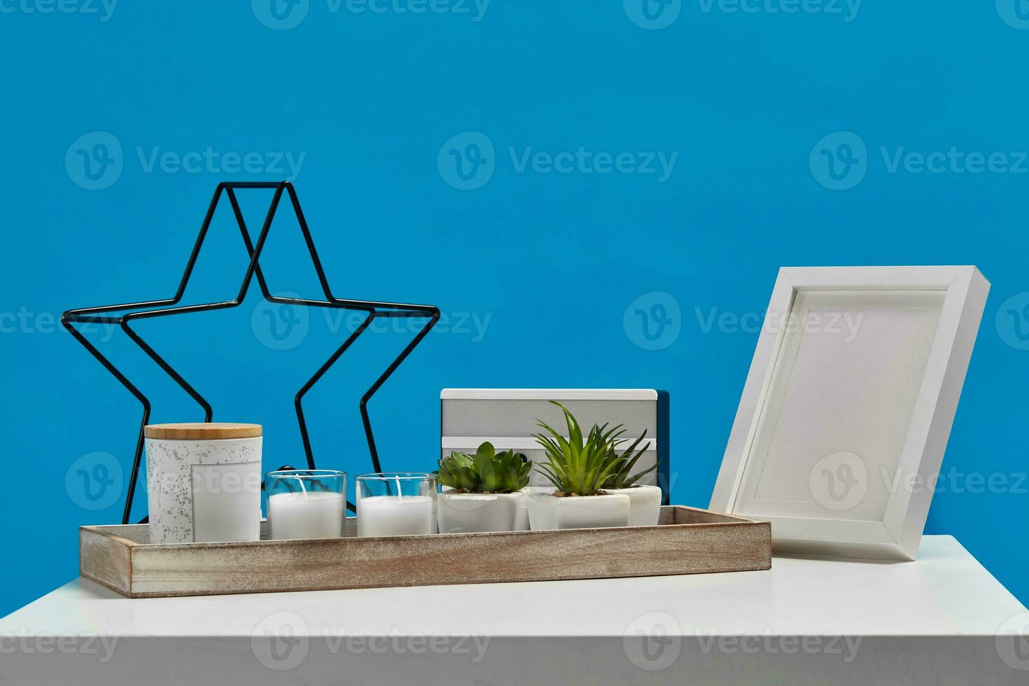 blanc tableau, en bois supporter avec vert succulentes, deux bougies, pot avec copie espace. noir le fer étoile, lampe, vide photo Cadre. bleu Contexte. proche en haut