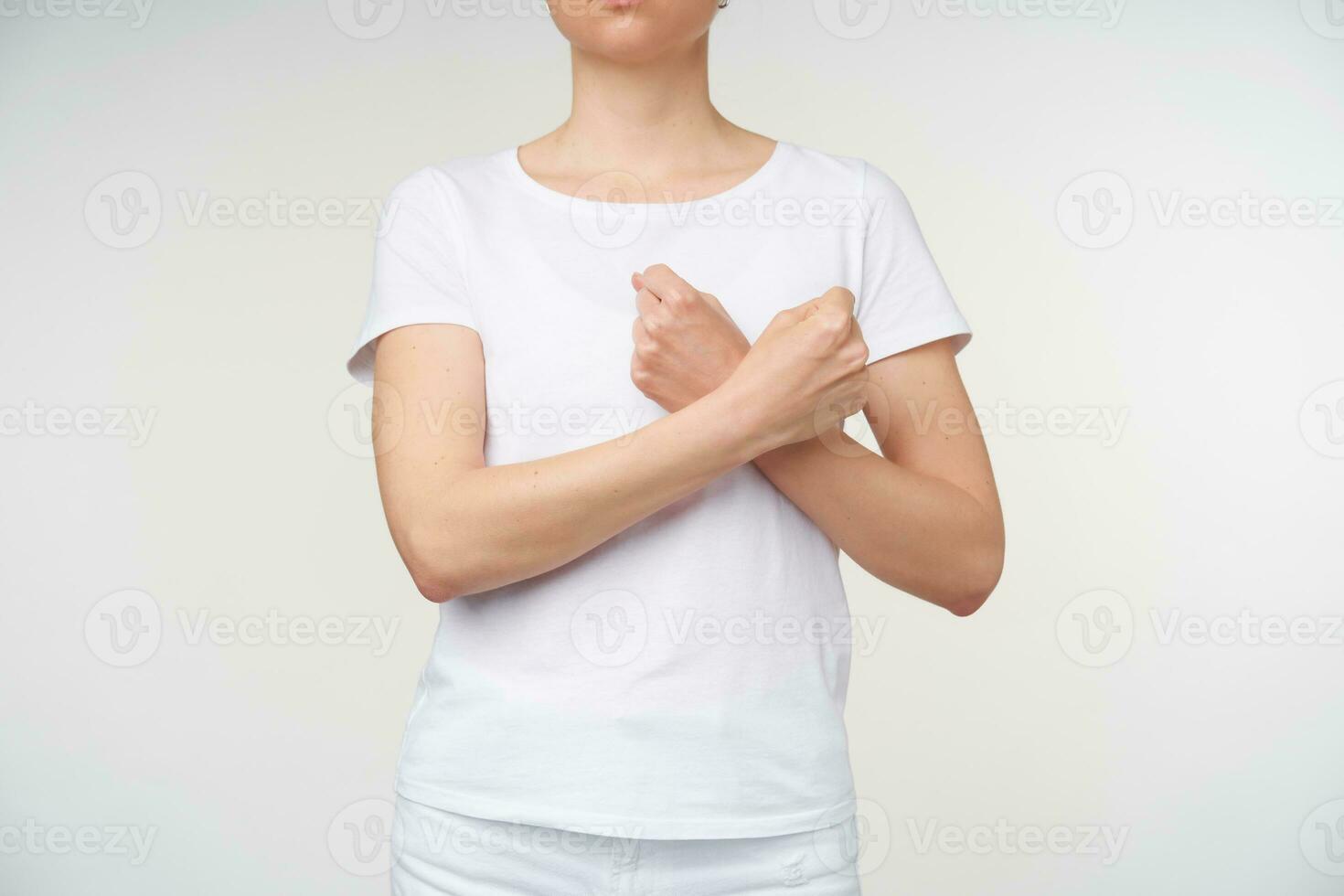 horizontal photo de Jeune femme serrant sa mains et en gardant il franchi tandis que exprimer pensées sans pour autant mots, isolé plus de blanc Contexte