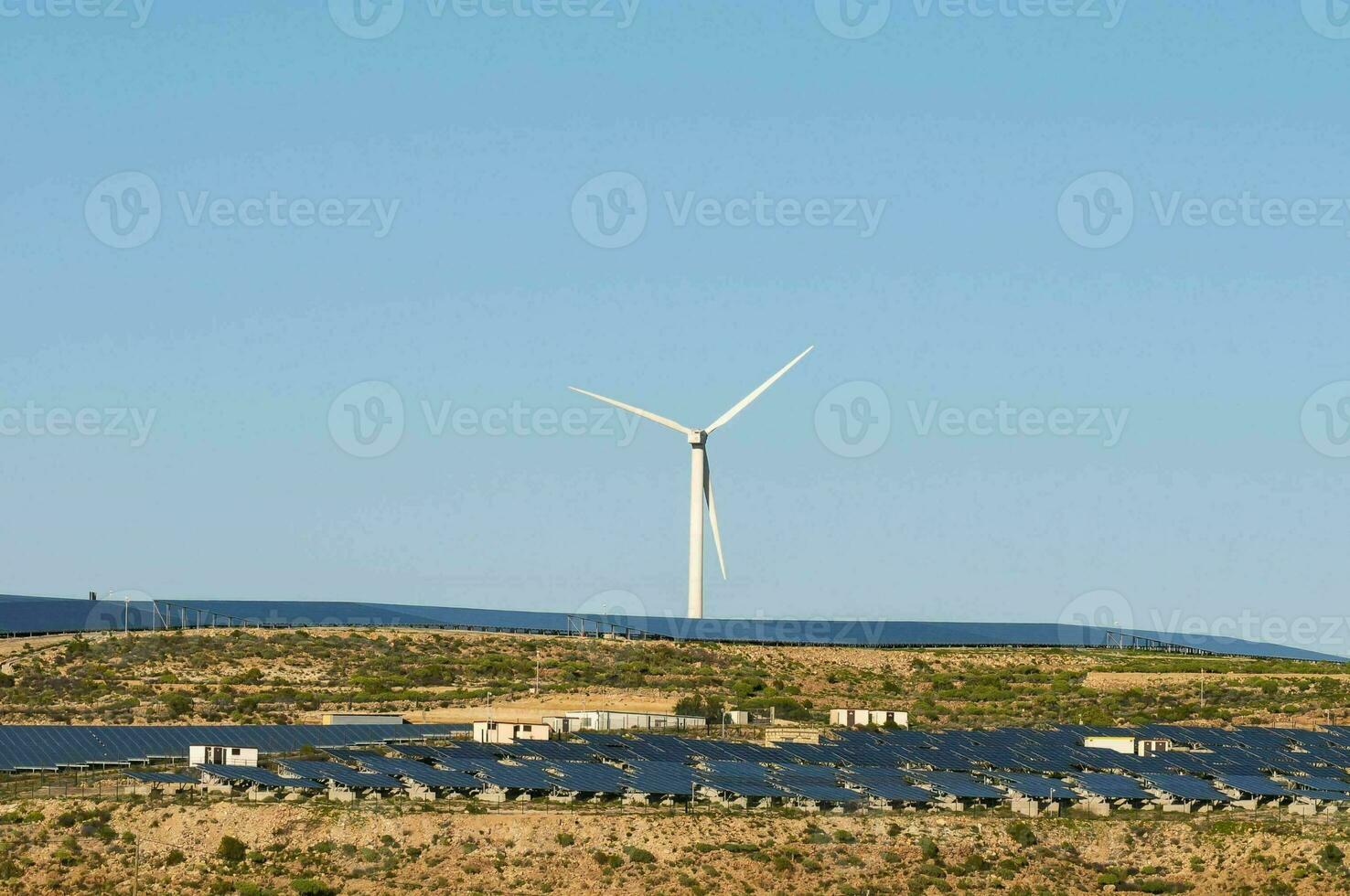 une vent turbine et solaire panneaux sur une flanc de coteau photo