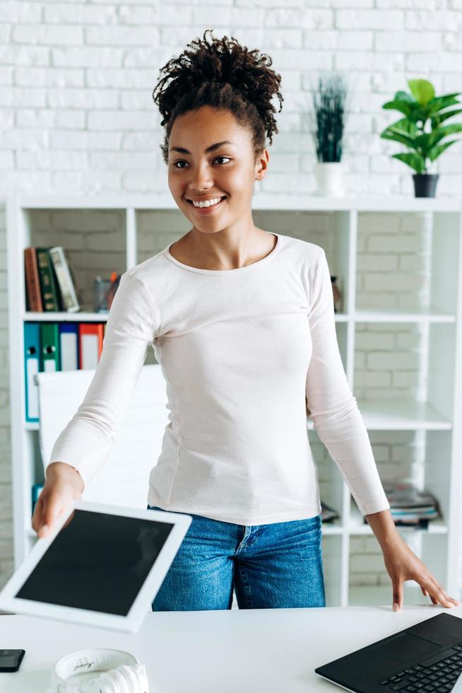 une belle femme d'affaires en vêtements décontractés tient une tablette comme si elle la donnait à quelqu'un photo