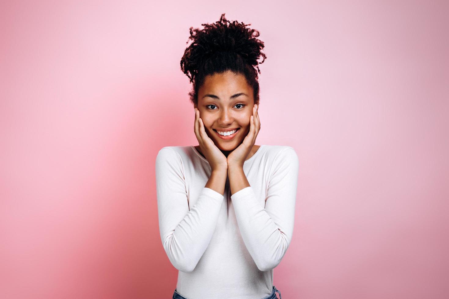 jolie fille afro se réjouit sincèrement sur un fond de mur rose photo