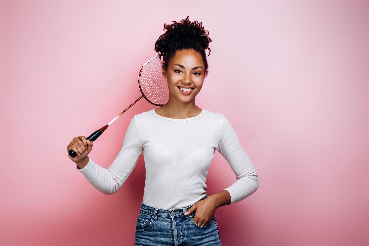 fille tenant une raquette de badminton sur fond de mur rose photo