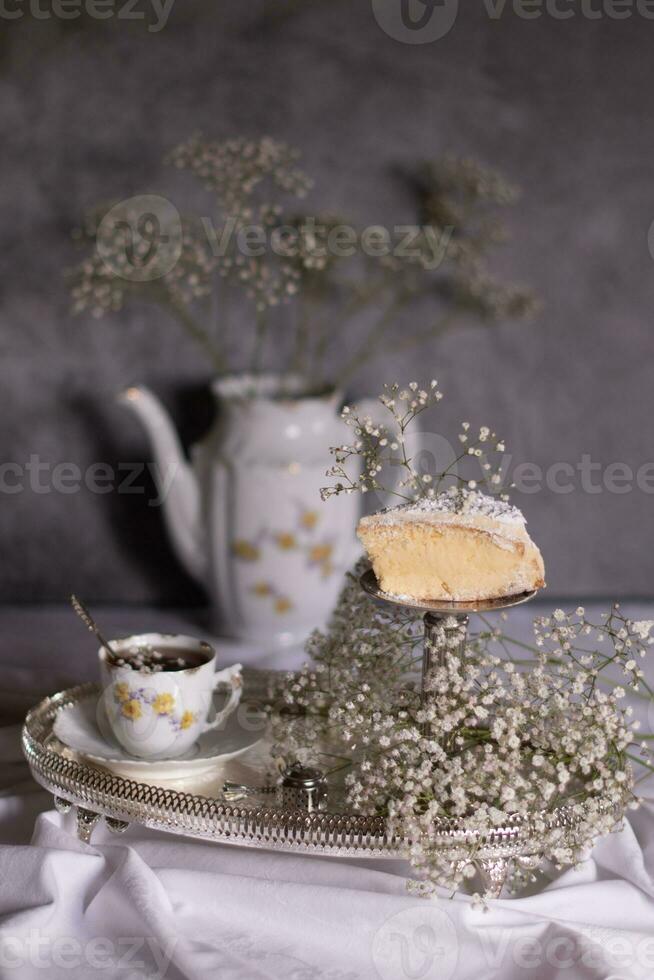 blanc encore la vie avec cheesecake et gypsophile et tasse de thé, lumière et aéré photo