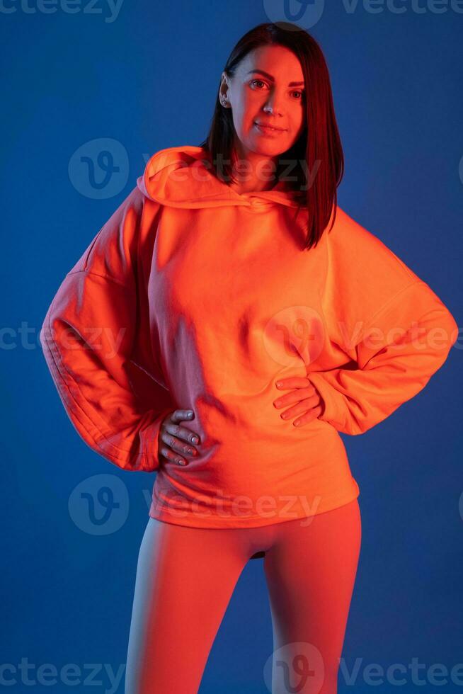 femme leggings et sweat à capuche dans Orange éclairage sur bleu Contexte photo