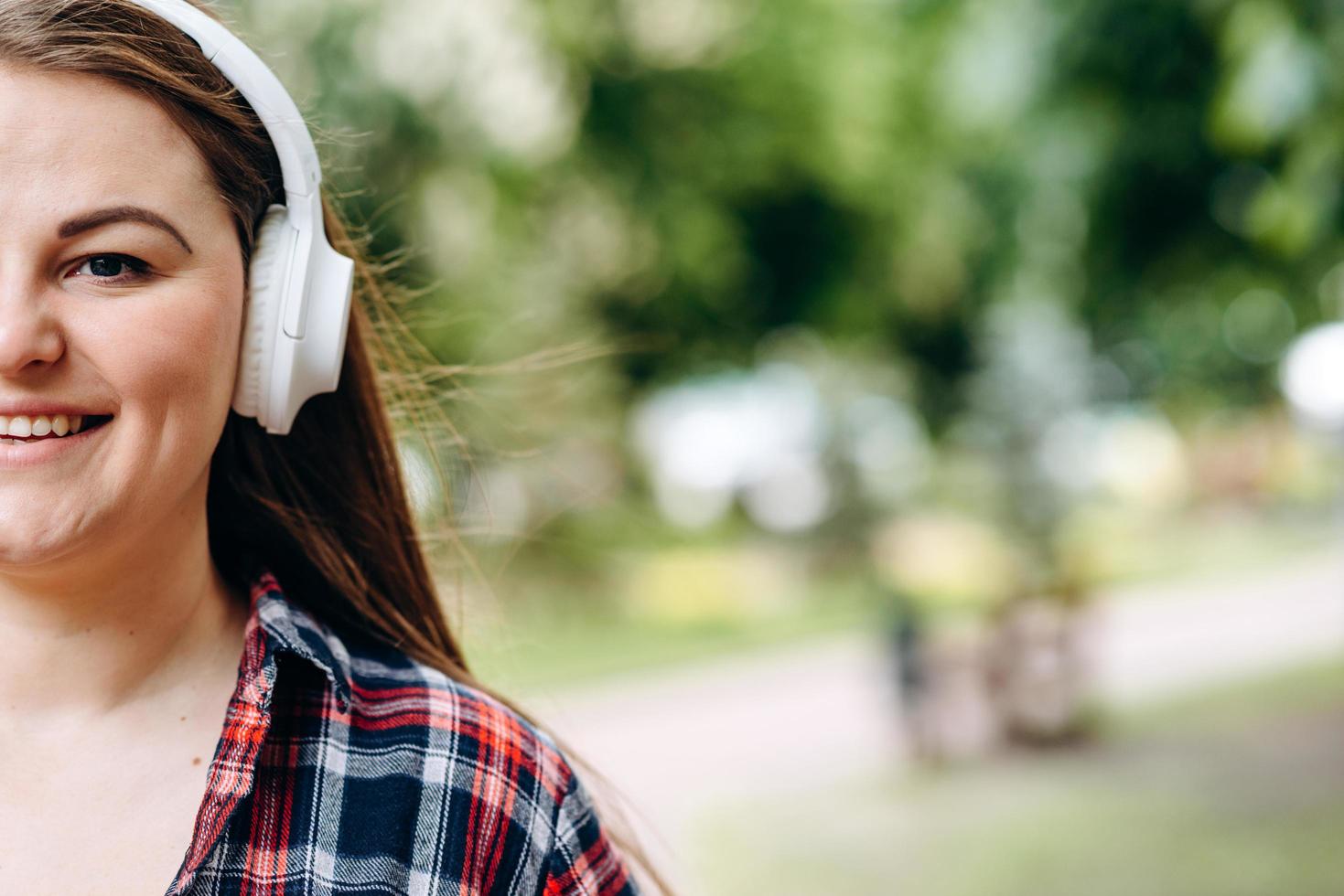 la photo montre la moitié du visage d'une jolie femme souriante portant des écouteurs blancs