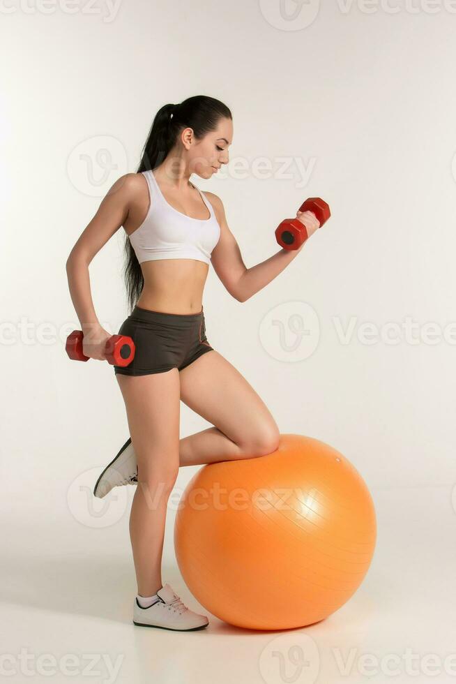 Jeune magnifique sportive avec haltères exercice sur fitball photo