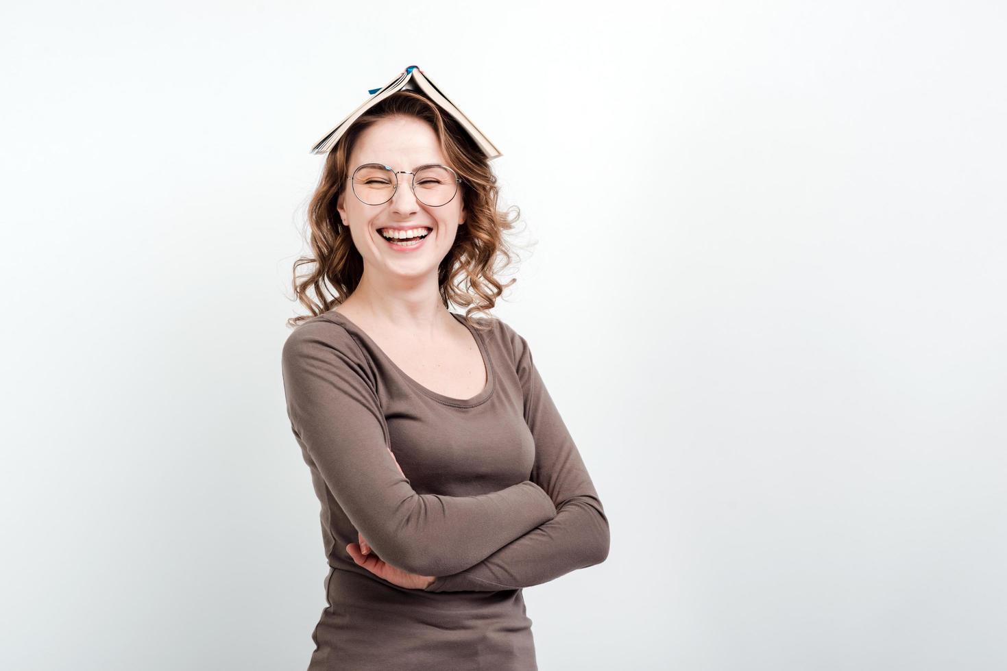 fille souriante dans des verres avec un livre ouvert sur la tête. photo