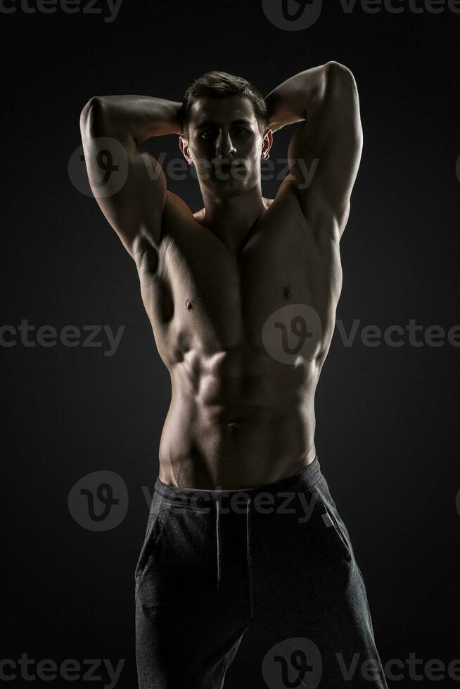 sexy torse nu bodybuilder poser, à la recherche à caméra sur noir Contexte. photo